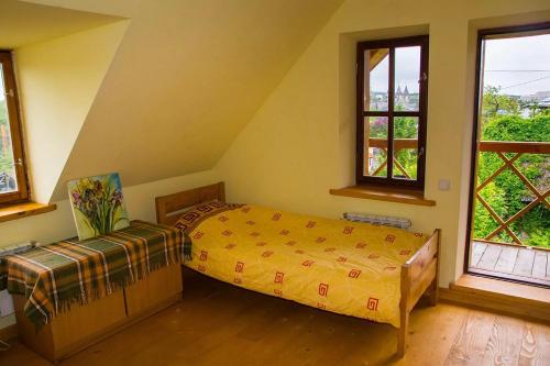 1 dormitorio con 1 cama y 2 ventanas en Tisnyi 7 Guest House, en Kamianets-Podilskyi