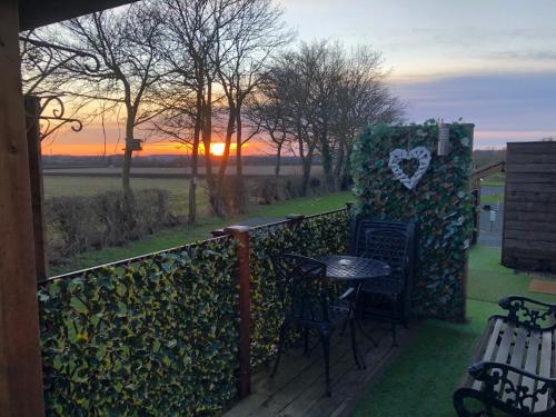 a balcony with a table and chairs and a sunset at Couple’s Lodge With Hot Tub in Lincolnshire