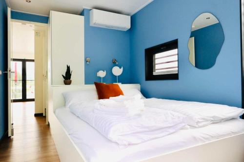 a bedroom with a white bed with a blue wall at Hausboot CALIENE - LP9 in Höxter