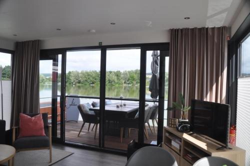 a living room with a table and a view of a lake at Hausboot Scarlett - LP5 in Höxter