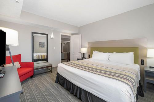 a hotel room with a large bed and a red chair at Country Inn & Suites by Radisson, Port Canaveral, FL in Cape Canaveral