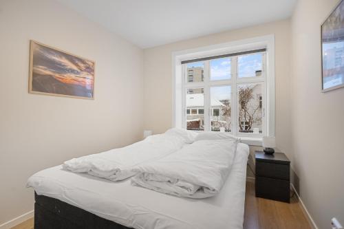 een wit bed in een kamer met een raam bij Homelike and Cozy Apt close to City Centre in Stavanger