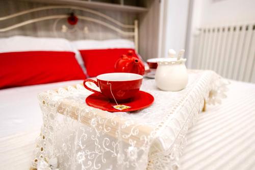 una tazza rossa e un piattino su un tavolo su un letto di Flower's House 24 - Central Apartment - Molfetta a Molfetta