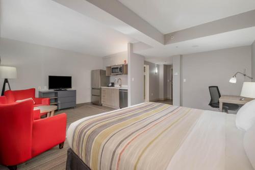 a hotel room with a bed and a red chair at Country Inn & Suites by Radisson, Port Canaveral, FL in Cape Canaveral