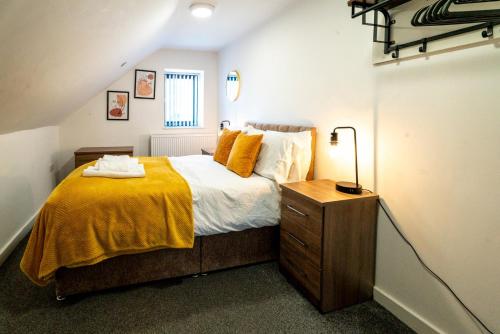 a bedroom with a bed with a yellow blanket at 3 Double BR | WiFi | Smart TV in Cardiff