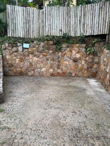 a stone wall with a wooden fence on it at Hospedagem Casa Maracujá in Trindade