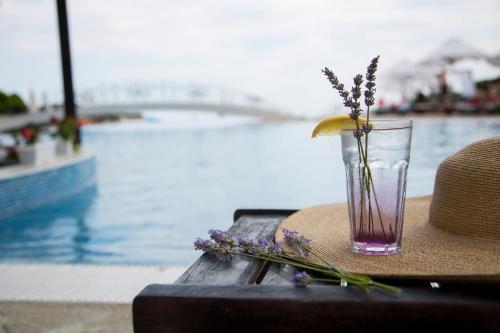 a vase with flowers and a hat on a table near a pool at Kaliakria Resort in Topola