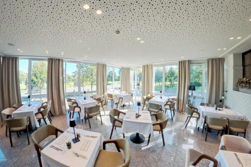 ein Restaurant mit Tischen, Stühlen und Fenstern in der Unterkunft Hotel Bessunger Forst in Roßdorf