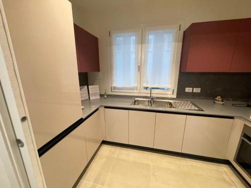 a kitchen with white cabinets and a sink at Nuovo Residence Serenissima Frontemare - Agenzia Cocal in Caorle