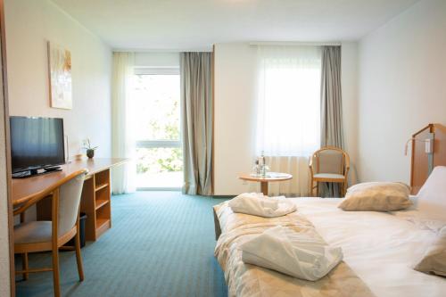 a hotel room with two beds and a desk and a television at Hotel Bessunger Forst in Roßdorf