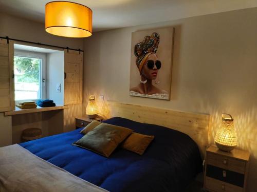 Un dormitorio con una cama azul con una mujer con gafas de sol. en Gîte 3* La Colinette, Lac du Bourget(3 km), en Saint-Pierre-de-Curtille