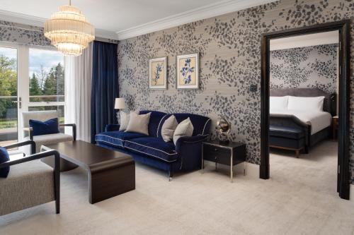 a living room with a blue couch and a bed at Fairmont Windsor Park in Windsor