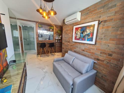 a living room with a couch and a brick wall at Apartamento em boa viagem in Recife