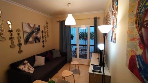 sala de estar con sofá negro y ventana en Bonito piso en calle Antolinez en Sevilla