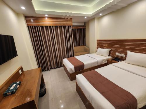 a hotel room with two beds and a desk at Sea Paradise in Cox's Bazar