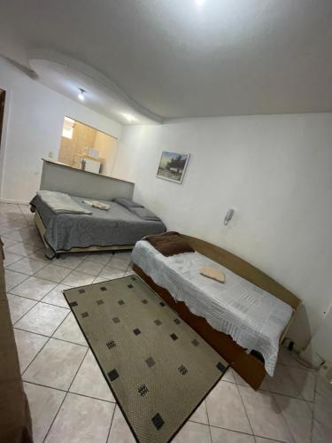 a bedroom with two beds and a rug at Apto Antonio Centro in Campos dos Goytacazes
