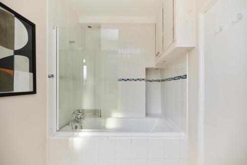 La salle de bains blanche est pourvue d'un lavabo et d'une douche. dans l'établissement The Elmington Estate Place - Elegant 1BDR Flat, à Londres