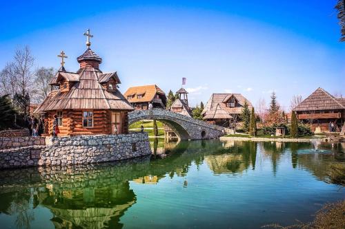 a church in the middle of a lake with a bridge at Etno selo Stanišići Hotel Pirg in Dvorovi