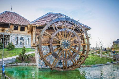 a wooden water wheel in front of a house at Etno selo Stanišići Hotel Pirg in Dvorovi