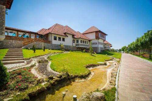 a large house with a grassy yard next to a river at Etno selo Stanišići Hotel Pirg in Dvorovi