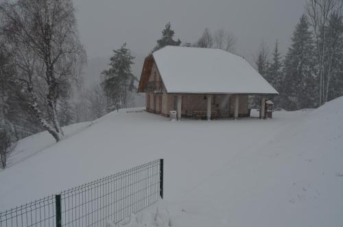 a barn covered in snow next to a fence at Holiday Home with Hot tub and Sauna Sabina in Rovte