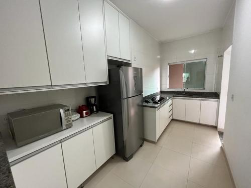 a kitchen with white cabinets and a stainless steel refrigerator at Apartamento Aconchegante in Capitólio