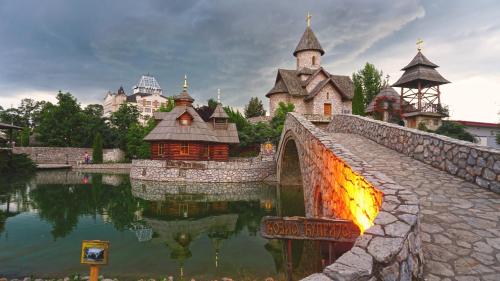 a bridge over a lake with a group of buildings at Etno selo Stanišići Hotel Pirg in Dvorovi