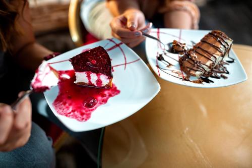 two plates of cake on a table with people eating it at Etno selo Stanišići Hotel Pirg in Dvorovi