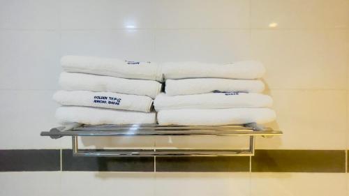 a stack of towels on a rack in a bathroom at Golden Tulip Ibadan in Ibadan