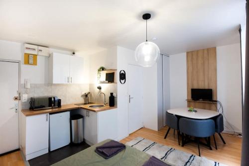 une cuisine avec des armoires blanches et une table dans une pièce dans l'établissement La Casa : Logement en centre ville, Cathédrale, à Amiens