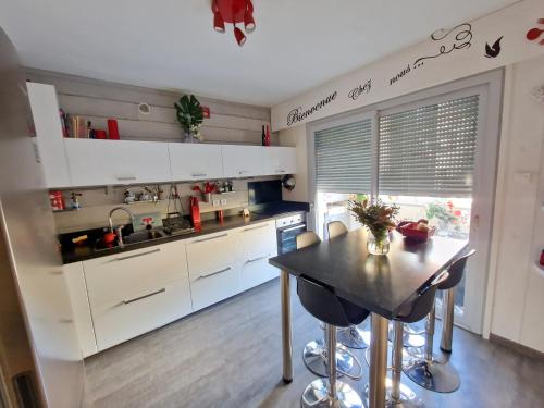 une cuisine avec des armoires blanches et une table avec des chaises dans l'établissement Aix Centre Cosy Calme Garage Terrasse, à Aix-les-Bains