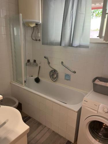 a bathroom with a tub and a washing machine at Sunset by the sea in Splitska