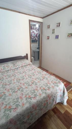 a bedroom with a bed with a floral bedspread at Pousada Sobre as Ondas - ILHA DO MEL - PR in Ilha do Mel
