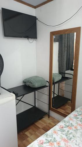 a room with a mirror and a tv and a bed at Pousada Sobre as Ondas - ILHA DO MEL - PR in Ilha do Mel