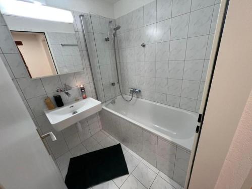 W łazience znajduje się biała wanna, umywalka i prysznic. w obiekcie Chesa Fischer Wohnung Palü ÖV-Inklusive w mieście Samedan