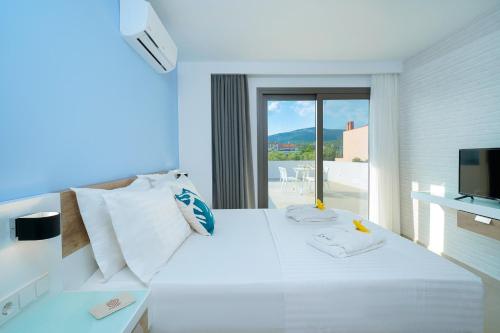 Schlafzimmer mit einem großen weißen Bett und einem Balkon in der Unterkunft Thassos OLIVIA RESORT in Potos
