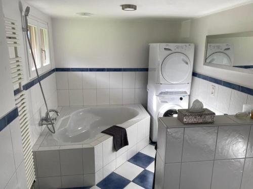 ein Badezimmer mit einer Badewanne und einer Waschmaschine in der Unterkunft Bijou Höfen 