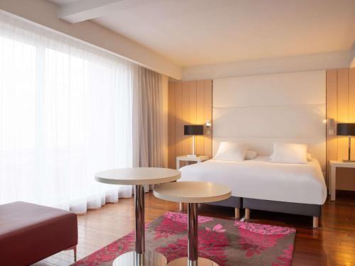 une chambre d'hôtel avec un lit et deux tables dans l'établissement Mercure Dieppe La Présidence, à Dieppe