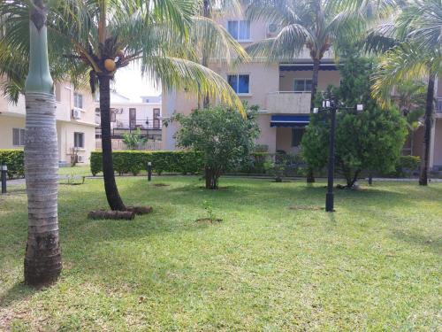 a park with palm trees in front of a building at Le Dattier - Three bedroom apartment - Coquillage in Flic-en-Flac