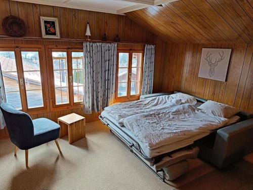 1 dormitorio con 1 cama, 1 silla y ventanas en Chalet Hasliblick Brienzwiler en Brienzwiler