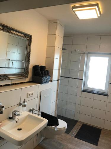 La salle de bains est pourvue d'un lavabo, de toilettes et d'un miroir. dans l'établissement Schöfferles Ferienwohnung, à Keidelheim