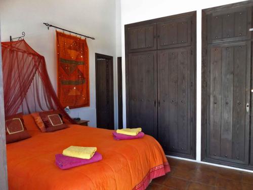 ein Schlafzimmer mit einem orangenen Bett mit zwei Handtüchern darauf in der Unterkunft Casa Almendros in Sedella