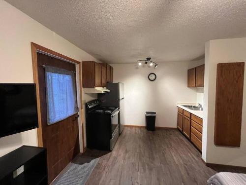 a small kitchen with a black refrigerator and wooden cabinets at Tomah Apartment - 201 E Veterans Unit J in Tomah