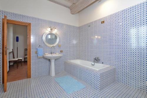 baño de azulejos azules con bañera y lavamanos en Villa Piandisette, en Cetona