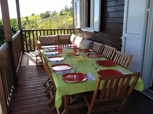 a green table with red plates and glasses on a deck at Chalet Floricia974, meublé de tourisme in Saint-Paul