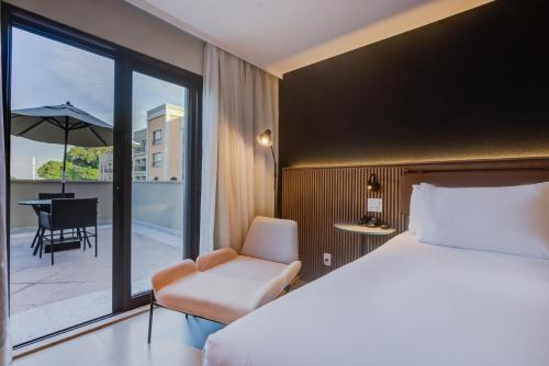 a bedroom with a bed and a chair and a balcony at Hilton Garden Inn São José do Rio Preto in Sao Jose do Rio Preto