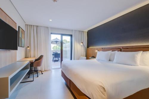 ein Hotelzimmer mit einem großen Bett und einem Schreibtisch in der Unterkunft Hilton Garden Inn São José do Rio Preto in Sao Jose do Rio Preto