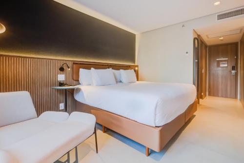 a bedroom with a large bed and two chairs at Hilton Garden Inn São José do Rio Preto in Sao Jose do Rio Preto