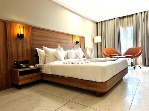 a bedroom with a large bed with a wooden headboard at The Sky Imperial Hotel Kailash in Jamnagar