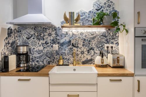 a kitchen with a white sink and a blue and white wallpaper at Chic & Comfort Homes in Central Volos # 3 in Volos